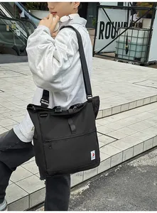 Detail of black large capacity utility tote bag with wide strap and logo tag
