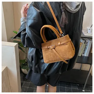 Detailansicht der braunen Wildlederbeuteltasche mit Gürtelschnalle und Tragegriffen