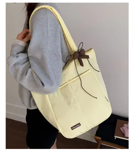 Detail of light yellow canvas tote bag featuring 3D brown bow and ChicCraze leather tag