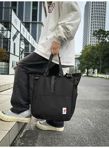 Detail of black high-capacity tote bag with side logo and adjustable straps in city setting