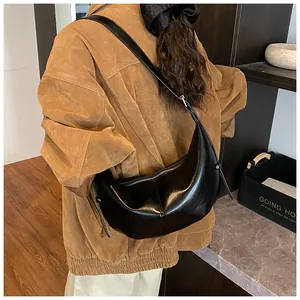 Detail view of black moon-shaped hobo bag with glossy finish and adjustable strap