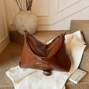 Sac hobo croissant marron brillant avec bandoulière en cuir et plaque en métal