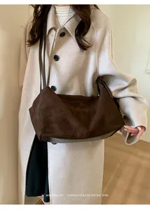 Detail of dark brown suede tote bag with leather piping on a minimalist wool coat