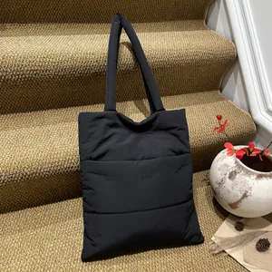 Large black quilted nylon tote bag with padded straps for daily commuting and laptop storage