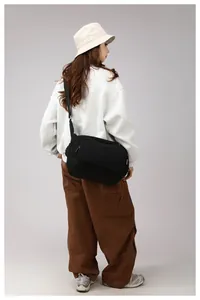 Close-up of black nylon crossbody bag with adjustable strap and side pocket on model