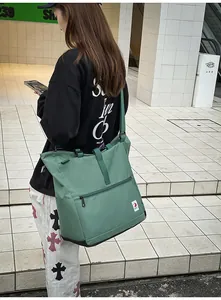 Detail view of large green canvas tote bag with front zip pocket and stylish strap