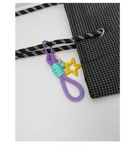 Detail of grid canvas tote featuring a colorful detachable charm and woven drawstring