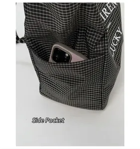 Detail shot of the side pocket on a checkered tote bag holding a mobile phone