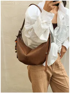 Detail view of brown leather hobo bag with colorful wooden beads and silver ring buckle