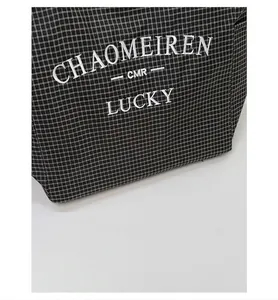 Close-up of black and white checkered canvas tote bag with exquisite letter embroidery