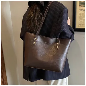Detail of dark brown leather tote bag with gold HOSOMU logo and vintage studs