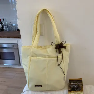 Pale yellow quilted puffer tote bag with ribbon charm and chic brand label detail