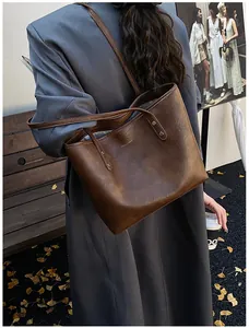 Detail view of deep brown faux leather tote bag with gold logo lettering on shoulder strap