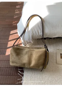 Detail of a khaki suede tote bag with slim brown shoulder straps in a retro home setting