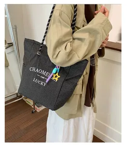 Detail of checkered canvas tote bag with thick braided rope handle and star charm