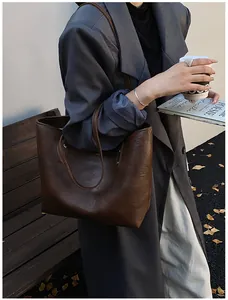 Detail of vintage brown leather tote bag showing texture and slim shoulder straps