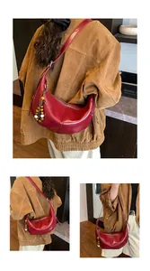 Detail of dark red crescent leather bag with retro wooden bead charm and zipper closure