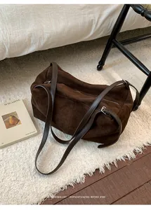 Detail of dark brown suede tote bag featuring adjustable shoulder strap and silver hardware