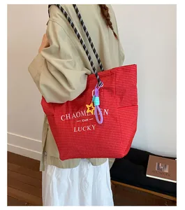 Detail of red plaid canvas tote bag with woven handles and colorful star pendant
