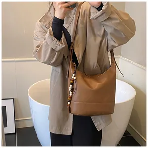 Detail der braunen Hobo-Tasche aus Leder mit weißer Ziernaht und Holzperlen-Quaste