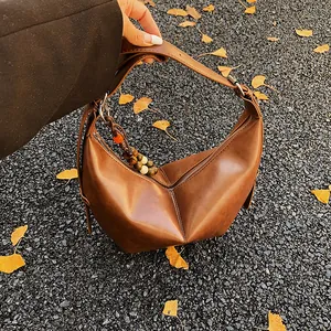 Vintage brown leather croissant bag with geometric folds and colorful beaded strap charm