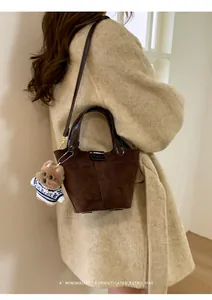 Detail of dark brown suede bucket bag with a cute puppy charm and golden hardware