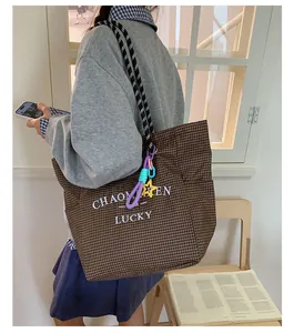 Detailed view of brown checkered tote bag with braided rope handles and lucky print