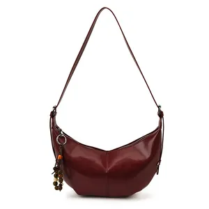 Minimalist wine red crescent shoulder bag in sleek leather with decorative bead charm