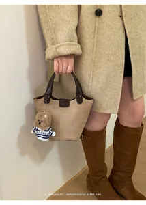 Close-up of retro khaki suede bucket bag with dark brown handle and a cute bear charm