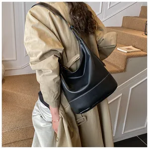 Detail der schwarzen Leder-Beuteltasche mit weißen Kontrastnähten und goldener Schnalle