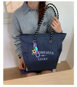 Detail of navy blue plaid tote bag with woven rope handles and star charm pendant