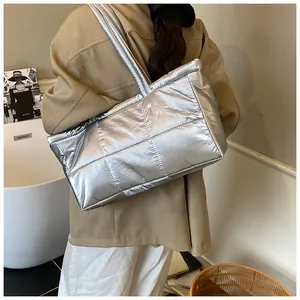 Foto lifestyle della grande borsa tote trapuntata argento portata a spalla in un interno