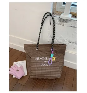Detail of brown checkered canvas tote bag with thick rope handles and colorful charms