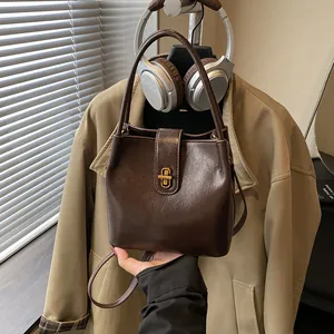 Retro dark brown leather bucket bag with gold lock and shoulder strap for autumn fashion