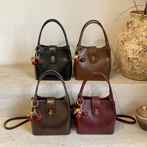 Vintage glossy leather bucket bags in black, brown, and red with cherry charms