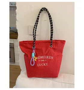 Detail of red checkered canvas tote with woven rope handles and star charm accessory
