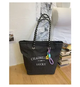 Detail view of canvas tote bag with black and white plaid pattern and letter embroidery