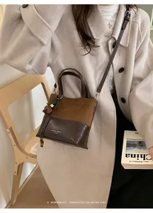 Detail of a minimalist two-tone bucket bag styled with a beige coat and vintage decor
