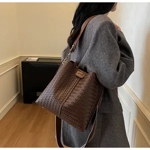 Detail of a brown woven leather bucket bag featuring dual straps and textured craftsmanship