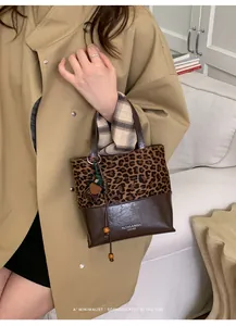 Detail of leopard print patchwork bucket bag with wood bead charm and logo lettering