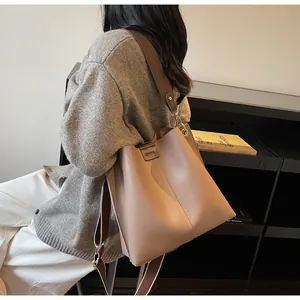 Detailed back view of a light brown bucket bag featuring wide woven strap and logo patch