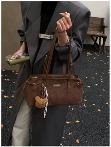 Close-up of brown suede tote bag with metal logo, cute bear charm and fashion accessories