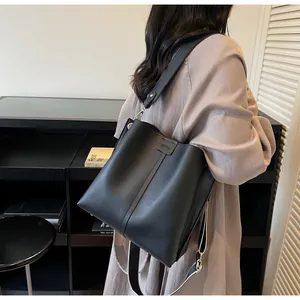 Detail of black faux leather bucket bag showing vertical stitching and gold hardware