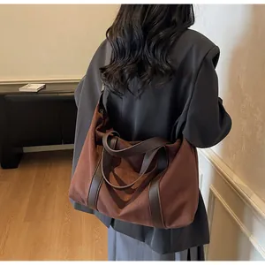 Detail view of large dark brown suede tote bag carried by a model in a minimalist setting