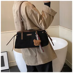 Detail of retro shoulder bag with teddy bear charm and brown leather trim accents