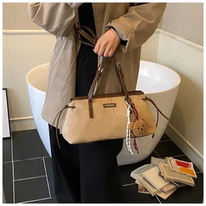 Detail of khaki suede tote bag with brown leather handles and cute plush bear charm