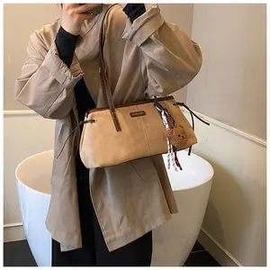 Detail of beige suede tote bag with brown leather trim and cute teddy bear pendant