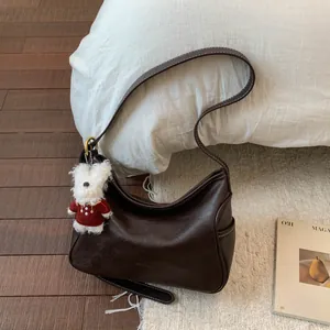 Détail du sac hobo en cuir marron foncé avec surpiqûres et breloque lapin en peluche