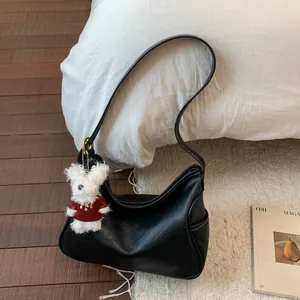 Détail du sac demi-lune noir avec surpiqûres blanches et charmant ours en peluche