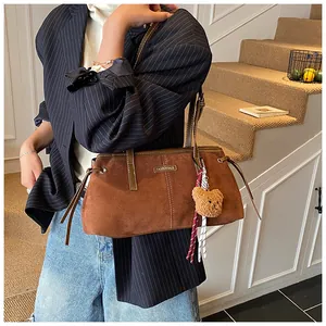 Detail view of brown faux suede tote bag with cute bear charm and metal fashion logo